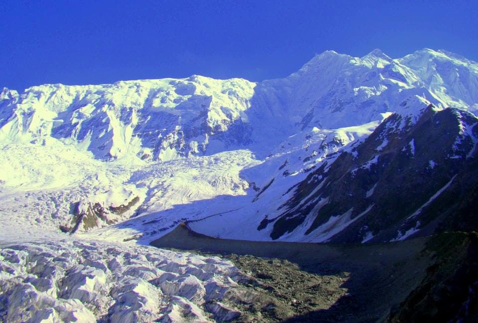 The ice seracs and snowfields of the Rakaposhi glacier below its summit ridge under a deep blue sky