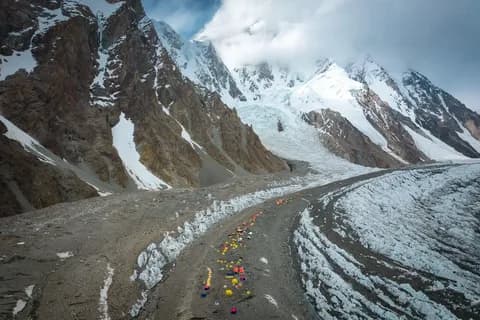 A colourful camp spread along the rocky median of a glacier between rock and ice slopes