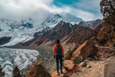 Trekker in an orange jacket looking down over the crevassed ice of the Rakaposhi glacier