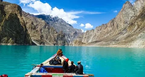 Boat carrying travellers across the turquoise water of a Hunza lake between bare rocky slopes