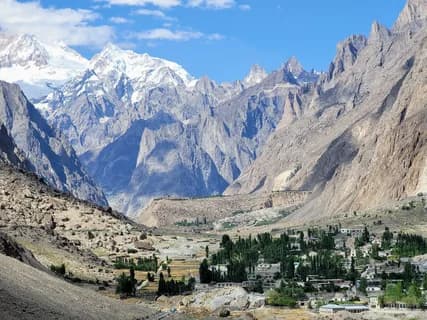 The green terraces of Hushe village among bare rock spires with snow-covered Masherbrum above