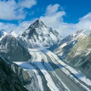 Snow-covered summit pyramid above a glacier flowing between dark rock ridges