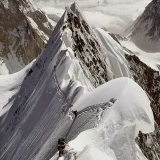 Snow-covered ridge line climbing between high peaks above a glacier