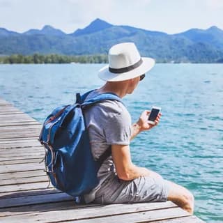 Traveller sitting on a wooden jetty beside a mountain lake
