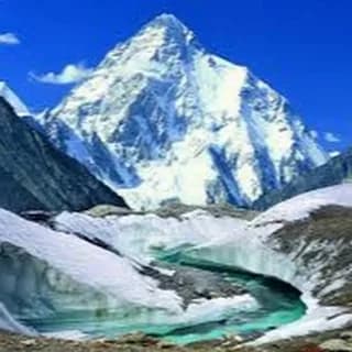 Snow-covered pyramid peak rising above a glacier under a deep blue sky