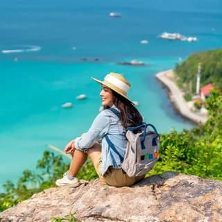 Traveller sitting on a rock above turquoise coastal water