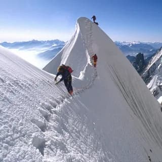 Climbers on a snow ridge, a trail of footprints leading towards the summit
