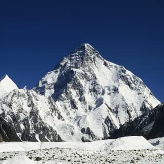 Snow-covered peak above the glacier tongue of a high mountain valley