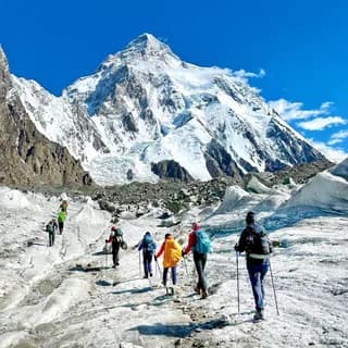 Roped team of mountaineers trekking across a glacier towards distant peaks