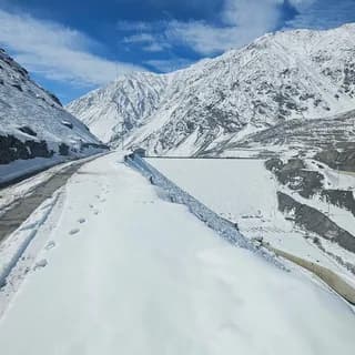 Snow-covered ridge with a trail of footprints leading towards distant peaks