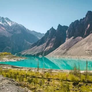 Turquoise alpine lake below dark rocky peaks, with a small boat moored on the water
